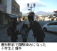 写真：豊科駅前で顔馴染みになった小学生と握手