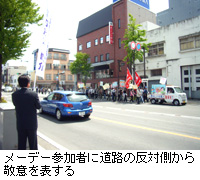 写真：メーデー参加者に道路の反対側から敬意を表する