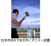 写真：松本市郊外で杭を手にポスター設置