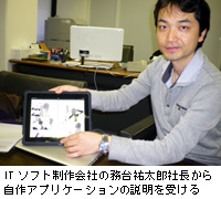 写真：ITソフト制作会社の務台祐太郎社長から自作アプリケーションの説明を受ける