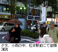 写真：夕方、小雨の中、松本駅前にて街頭演説