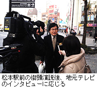 写真：松本駅前の街頭演説後、地元テレビのインタビューに応じる